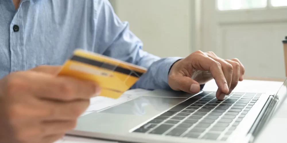 Businessman using laptop and credit card for e-commerce business at home.