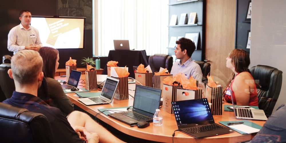 man standing in front of people sitting beside table with laptop computers